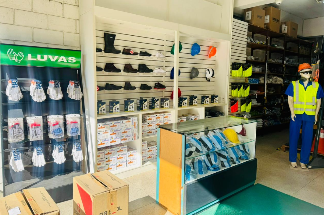 Área de entrada da loja Cobequi com vitrine de luvas, prateleiras de calçados e manequim com EPI
